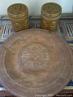 Photo showing the full contents: two brown ceramic lidded jars and large round carved wood tray with a geometric central pattern.