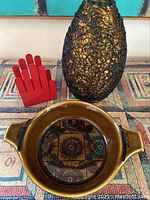 Overall view of the three items: ceramic Norway dish, black wire lamp shade, red hand-shaped napkin holder.