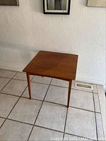Front view of vintage teak side table with square stained top and tapered legs