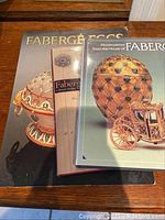 Front covers of three Fabergé books, showing Fabergé eggs in various ornate designs including a carriage egg.
