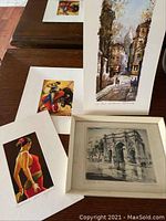 Photo showing several art prints including a flamenco dancer, a city street scene, and an architectural sketch in a frame.
