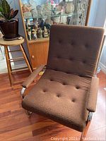 Full front view of sling chair showing tufted cushion and chrome frame