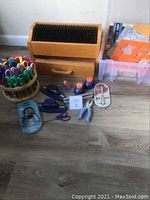 Full view of scrapbooking supplies including wooden 31 day file holder with drawer, set of colorful decorative scissors on wooden spinning holder, paper punches, stencils, and crafting adhesives.