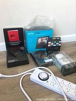 Photo showing all items together: K40 radar detector box, Echo Show box, Windows Vista Ultimate software box, emergency light sealed package, and timer power strip.