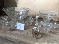 Overall view showing two crystal punch bowls with multiple matching cups and the Hofbaur lead crystal bell with gold accents.