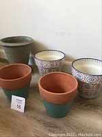 Photo showing the full set of five garden pots, two with patterned ceramic finish, two with sea foam green and terracotta, and one metal pot.