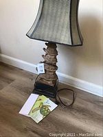 Turtle table lamp on floor showing stacked turtle base and shade with items placed beside it