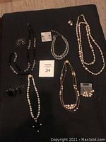 Photo showing all five necklaces and their matching pairs of earrings arranged on a black surface
