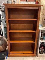 Front view of wooden bookcase showing 4 shelves and visible wear/scratches