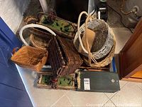 Overview photo showing multiple woven baskets stacked together, including whitewashed round basket, brown rectangular baskets, and green rustic planter box.