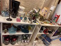 Two white shelves filled with vases, candle holders, bowls and decorative items