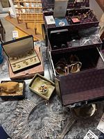 Overview of jewelry lot showing necklaces, jewelry box with earrings and bracelets, and a hand mirror.