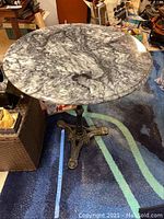 Top and angled view of round marble top table showing marble pattern and metal base.