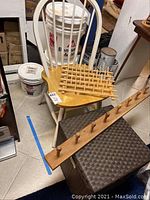 Wooden chair holding a wooden coat rack and a brown woven storage cube below it.