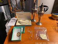 Full lot display on table showing all the items including the boxed bracelet, necklace chain, 14K gold charm, and salt & pepper shakers