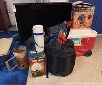 Full view of camping gear assortment including coolers, lantern, sleeping bag and other bags
