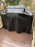 Grill covered with black vinyl protective cover on deck