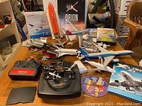 Wide shot of table showing multiple RC aircraft, model kits, parts and media