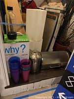 Photo showing SodaStream unit on its box, bread box, griddle, compost bucket and stacked colored cups