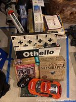 Overview photo of multiple boxed puzzles, board games, and electric toy car in a basement.
