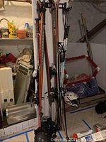 Photo showing skis, ski poles, and helmet arranged in basement with various background items.
