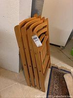 Four wooden folding chairs stacked together showing natural wood finish and folding design.