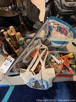 Photo showing multiple small baseball bats stored upright in a metal container with other miscellaneous items around them.