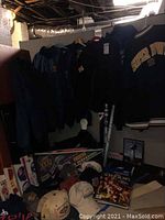 Photo showing a variety of Super Bowl jackets hanging, multiple hats, T-shirts, programs, posters, and wall pendant flags arranged below.