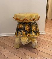 Side front view of ceramic turtle garden stool showing yellow seat with decorative orange trim and full body of turtle detailed with shell pattern and textured legs