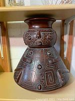 Front view of the vase showing tribal etched face and geometric designs on the body