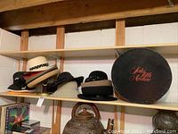 Shelf display featuring various hats and a black Saks Fifth Avenue hat box