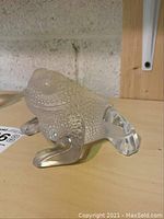 Three-quarter view of the frosted crystal frog on wooden shelf