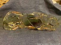 Side view of clear Baccarat crystal tiger figurine showing entire length and form on dark fabric background.