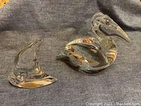 View showing Daum crystal pelican and fish sculptures on gray fabric background.
