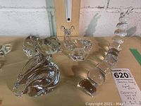 Table display of four crystal and glass animal figurines including a rabbit, deer, pig, and caterpillar in clear polished crystal and glass.