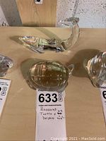 Photo of Baccarat crystal dolphin and turtle figurines on a wooden surface with a label showing measurements and identification.