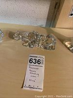 Top side view of clear crystal crouching lioness measuring 2.5 by 6 inches with handwritten label.