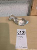 Front view of baccarat crystal duck figurine on a wooden surface with lot tag showing dimensions and description.