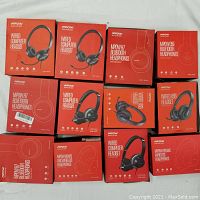 Boxed Mpow headphones, 12 units including wired and wireless models arranged in two rows, showing variety of headset types and models.