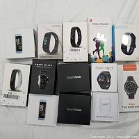 Multiple open-box smartwatch/fitness tracker boxes, assorted models.