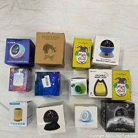 All eleven items in their packaging arranged on a flat surface, showing boxes for alarm clocks, night lights, and projection lamps.