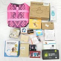 Overview of all items in the lot including floating vest, pet water bottle, multiple boxed items including dog training collars, nail grinder, hair clipper kit, and adapters.