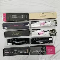 Packaging of 10 different hair appliances in their boxes arranged flat showing brand names and product categories.
