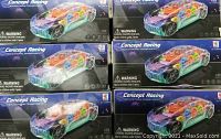 Photo of six boxed Concept Racing transparent educational toy cars, showing the packaging with colorful internal gears visible on the box art.