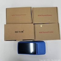 Top view of three boxed mini thermal printers and a blue POS terminal printer.