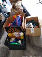 Outdoor yard toys including balls and dartboard in boxes, and box of large Christmas lights