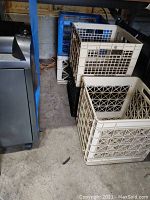 Photo showing five plastic crates stacked and positioned near tables, beige, black, and blue colors visible