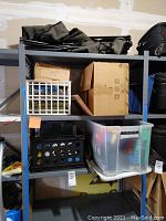 Full view of shelving unit with crates, boxes, and folded green fabric items