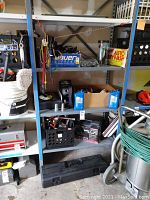 Full view of metal shelving with automotive items: bucket, motor oil, boxes, and other supplies.