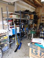 Wide angle view of the large metal shelving unit placed against garage wall, filled with boxes and items not included in sale.